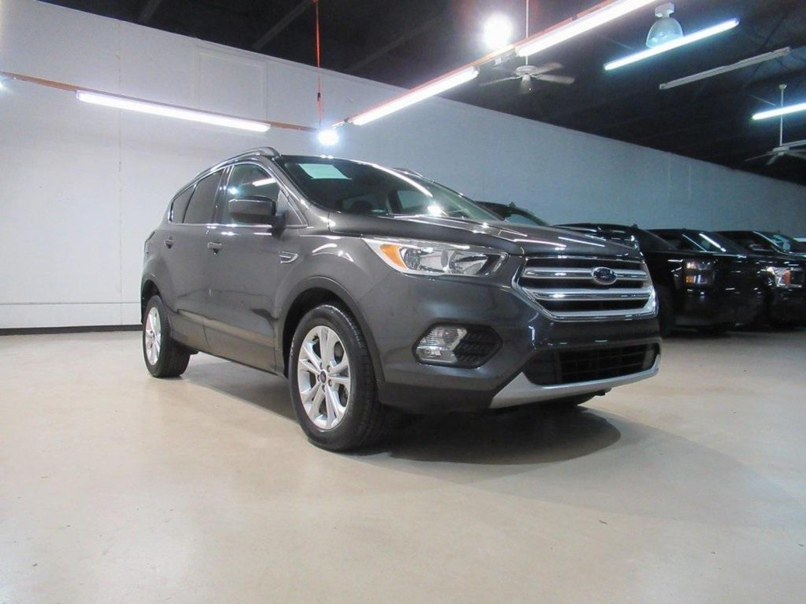 2018 Magnetic /Medium Light Stone Ford Escape SE (1FMCU0GD7JU) with an EcoBoost 1.5L I4 GTDi DOHC Turbocharged VCT engine, Automatic transmission, located at 15300 Midway Rd., Addison, 75001, (972) 702-0011, 32.958321, -96.838074 - HOME OF THE NO HAGGLE PRICE - WHOLESALE PRICES TO THE PUBLIC!! Escape SE, 4D Sport Utility, EcoBoost 1.5L I4 GTDi DOHC Turbocharged VCT, 6-Speed Automatic, FWD, Magnetic, Medium Light Stone Cloth. Odometer is 18027 miles below market average!<br><br>Magnetic 2018 Ford Escape SE<br><br>23/30 City/Hig - Photo #1