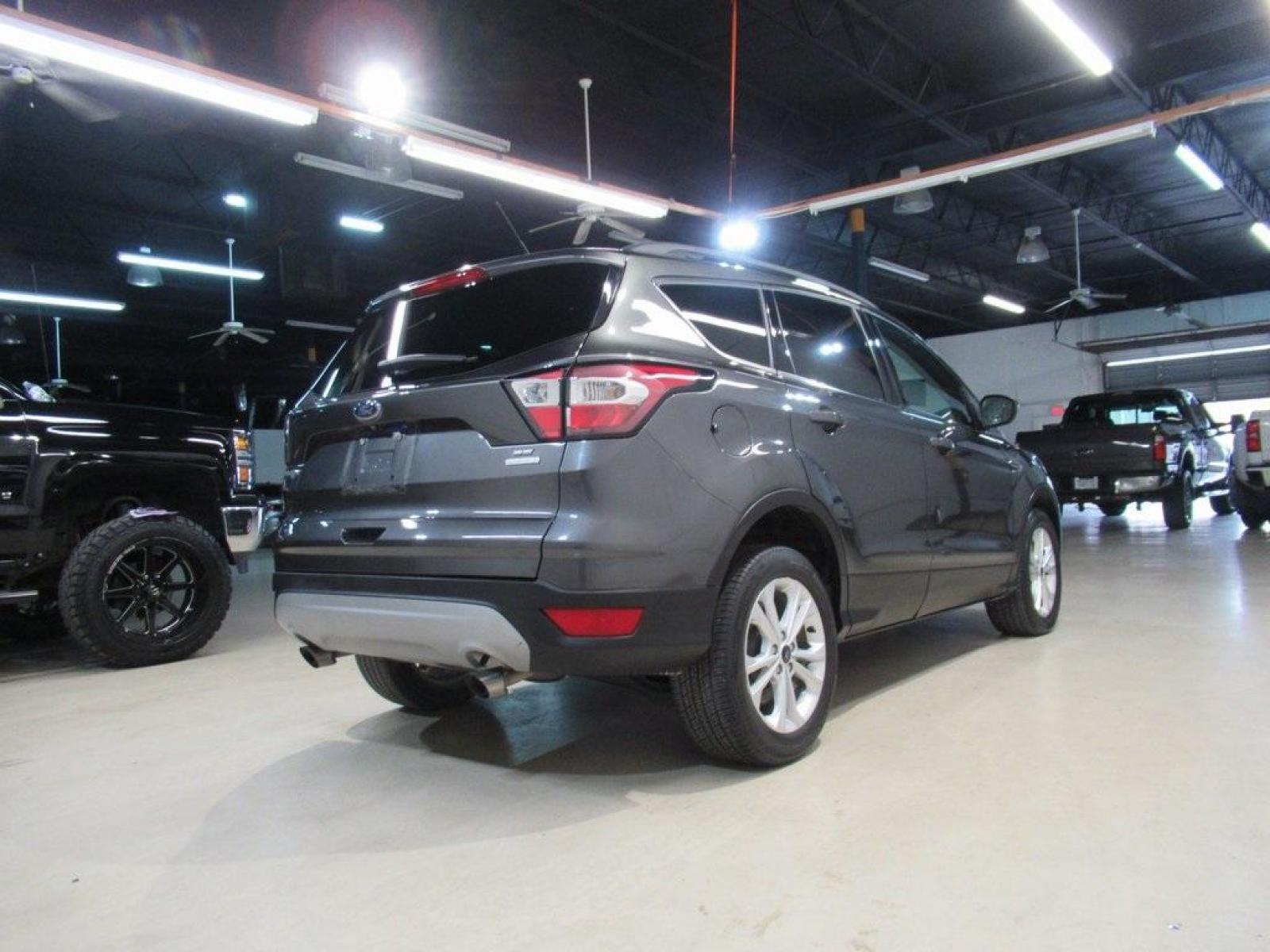 2018 Magnetic /Medium Light Stone Ford Escape SE (1FMCU0GD7JU) with an EcoBoost 1.5L I4 GTDi DOHC Turbocharged VCT engine, Automatic transmission, located at 15300 Midway Rd., Addison, 75001, (972) 702-0011, 32.958321, -96.838074 - HOME OF THE NO HAGGLE PRICE - WHOLESALE PRICES TO THE PUBLIC!! Escape SE, 4D Sport Utility, EcoBoost 1.5L I4 GTDi DOHC Turbocharged VCT, 6-Speed Automatic, FWD, Magnetic, Medium Light Stone Cloth. Odometer is 18027 miles below market average!<br><br>Magnetic 2018 Ford Escape SE<br><br>23/30 City/Hig - Photo #2