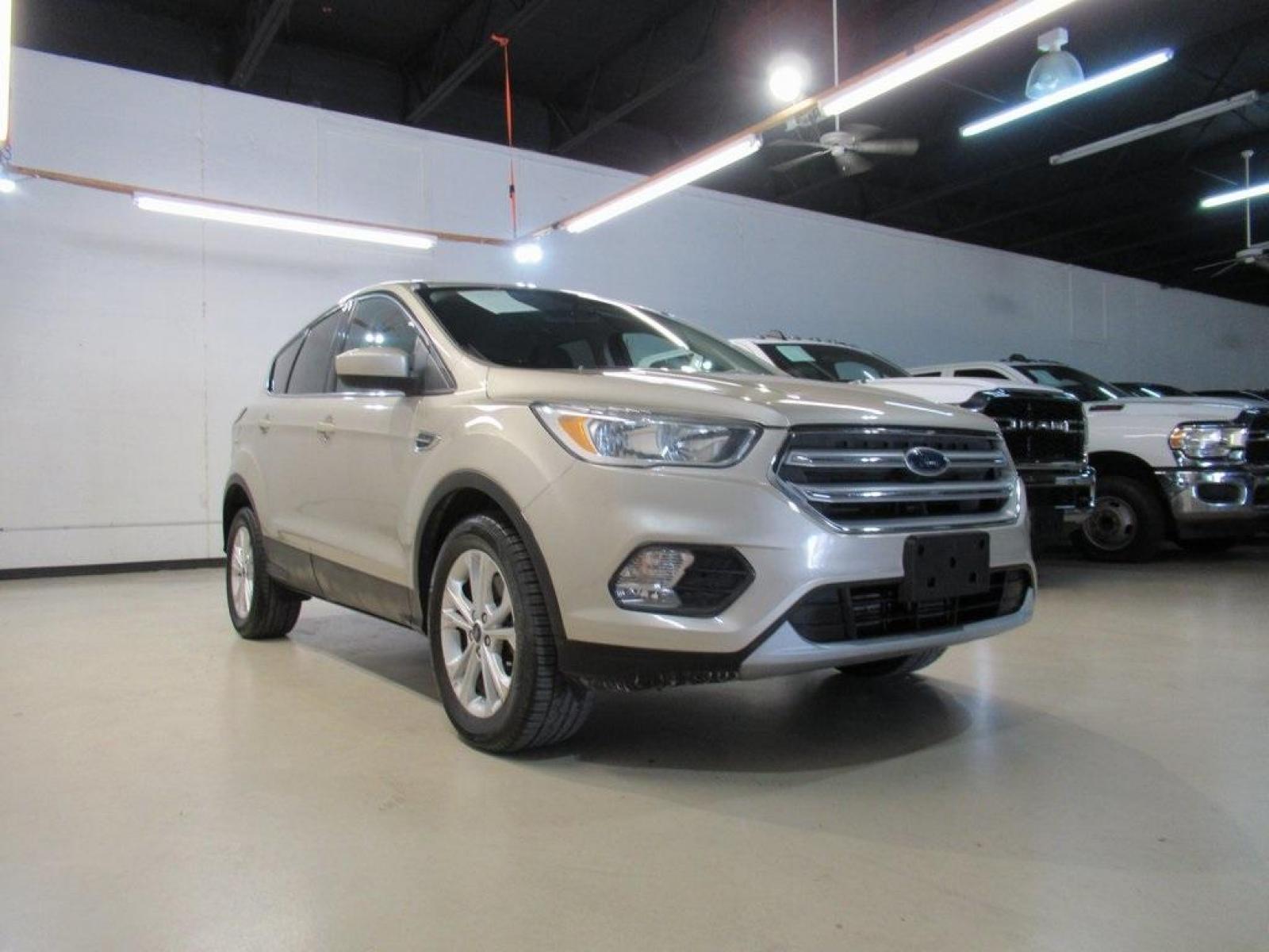2017 White Gold Metallic /Charcoal Black Ford Escape SE (1FMCU0G94HU) with an EcoBoost 2.0L I4 GTDi DOHC Turbocharged VCT engine, Automatic transmission, located at 15300 Midway Rd., Addison, 75001, (972) 702-0011, 32.958321, -96.838074 - HOME OF THE NO HAGGLE PRICE - WHOLESALE PRICES TO THE PUBLIC!! Escape SE, 4D Sport Utility, EcoBoost 2.0L I4 GTDi DOHC Turbocharged VCT, 6-Speed Automatic, FWD, Gold, Charcoal Black Cloth.<br><br>Gold 2017 Ford Escape SE<br><br>Recent Arrival! 22/29 City/Highway MPG<br><br>Awards:<br> * 2017 KBB.co - Photo #1